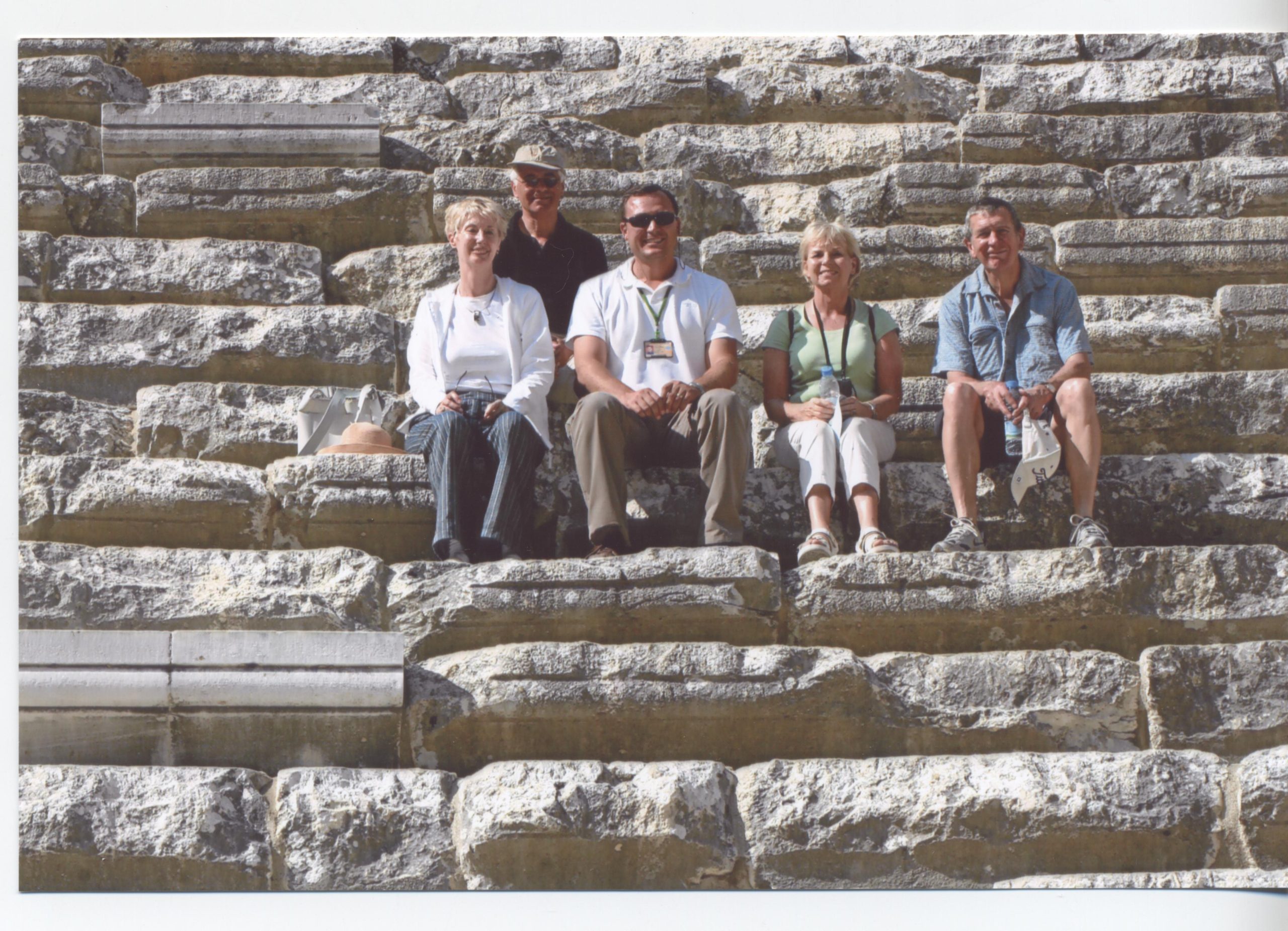 A guided tour group exploring the ancient stone steps of the Roman Theatre in Aspendos during a cultural excursion.